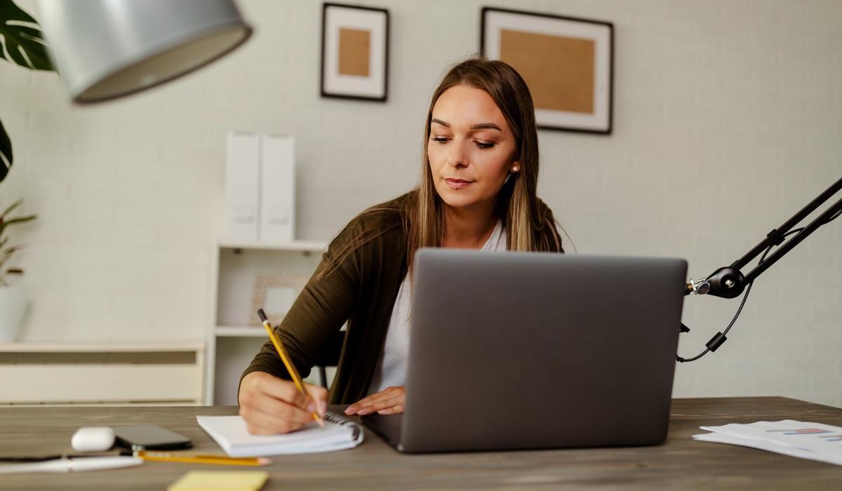 Mulher em sua mesa, escrevendo um briefing de design.