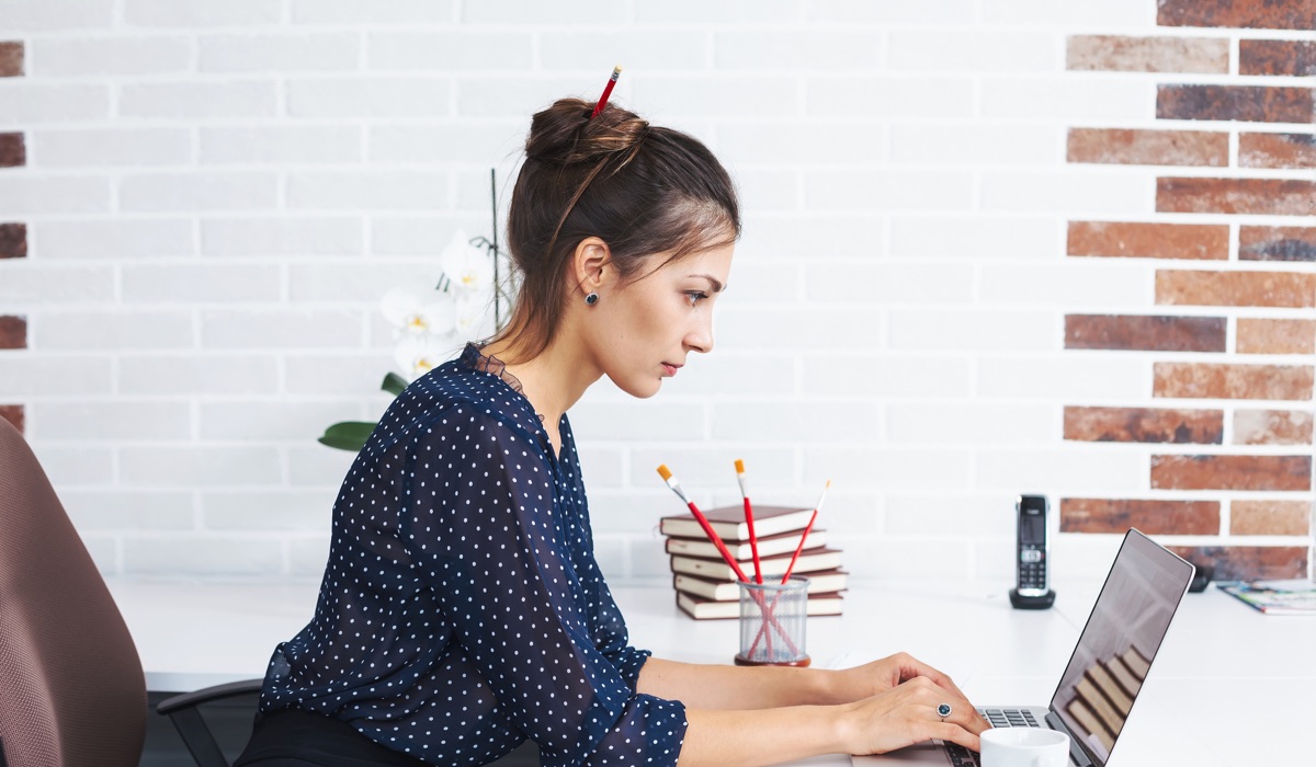 女人在她的电脑前，通过电子邮件向设计师发送设计简介。