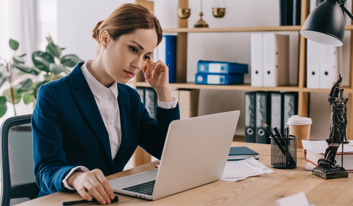 Pengacara wanita berjas bekerja pada laptop di tempat kerja di kantor.