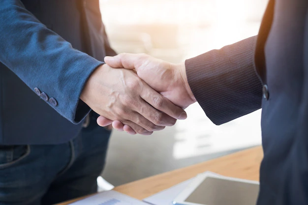 Foto gratis dos hombres de negocios confiados dándose la mano durante una reunión en la oficina, el éxito, el trato, el saludo y el concepto de socio