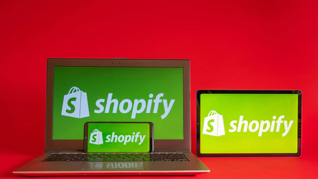 사진 도쿄 일본 2022년 6월 5일 최신 노트북 스마트폰에 표시되는 shopify 웹 페이지 및 빨간색 배경의 노트북 shopify iphone 로고