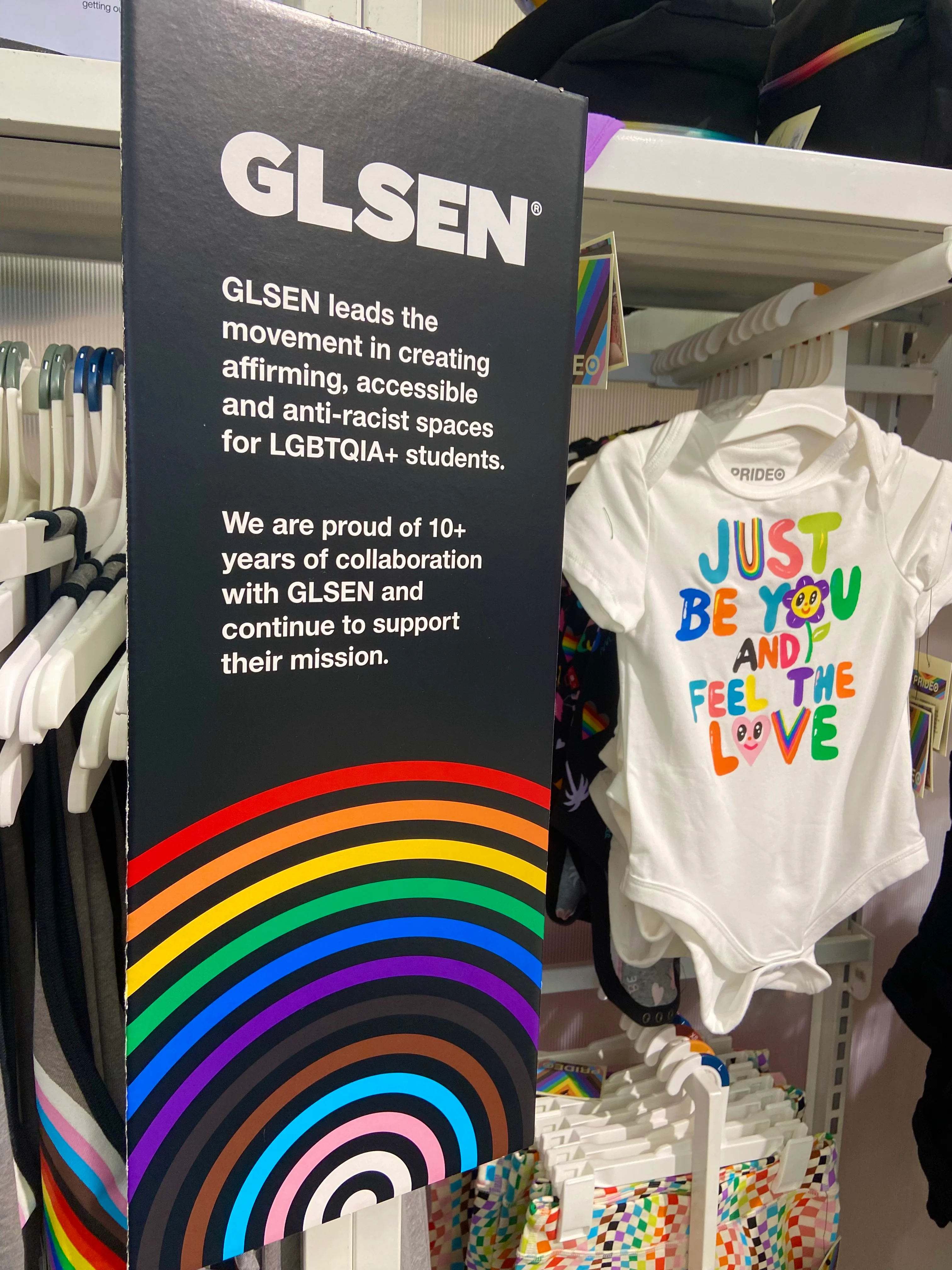 Un letrero colocado en un estante de ropa para niños promueve GLSEN, que "lidera el movimiento en la creación de espacios afirmativos, accesibles y antirracistas para estudiantes LGBTQIA+.