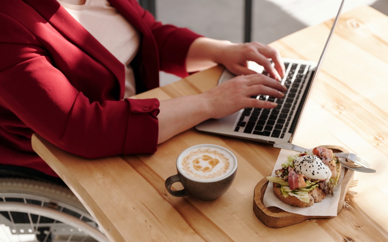 Una donna che lavora al computer con il pranzo sul tavolo