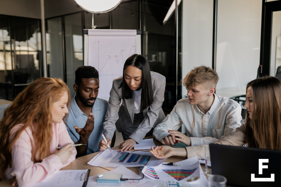 Imagen de un equipo de marketing discutiendo de forma colaborativa estrategias y analizando análisis de marketing juntos alrededor de una mesa.