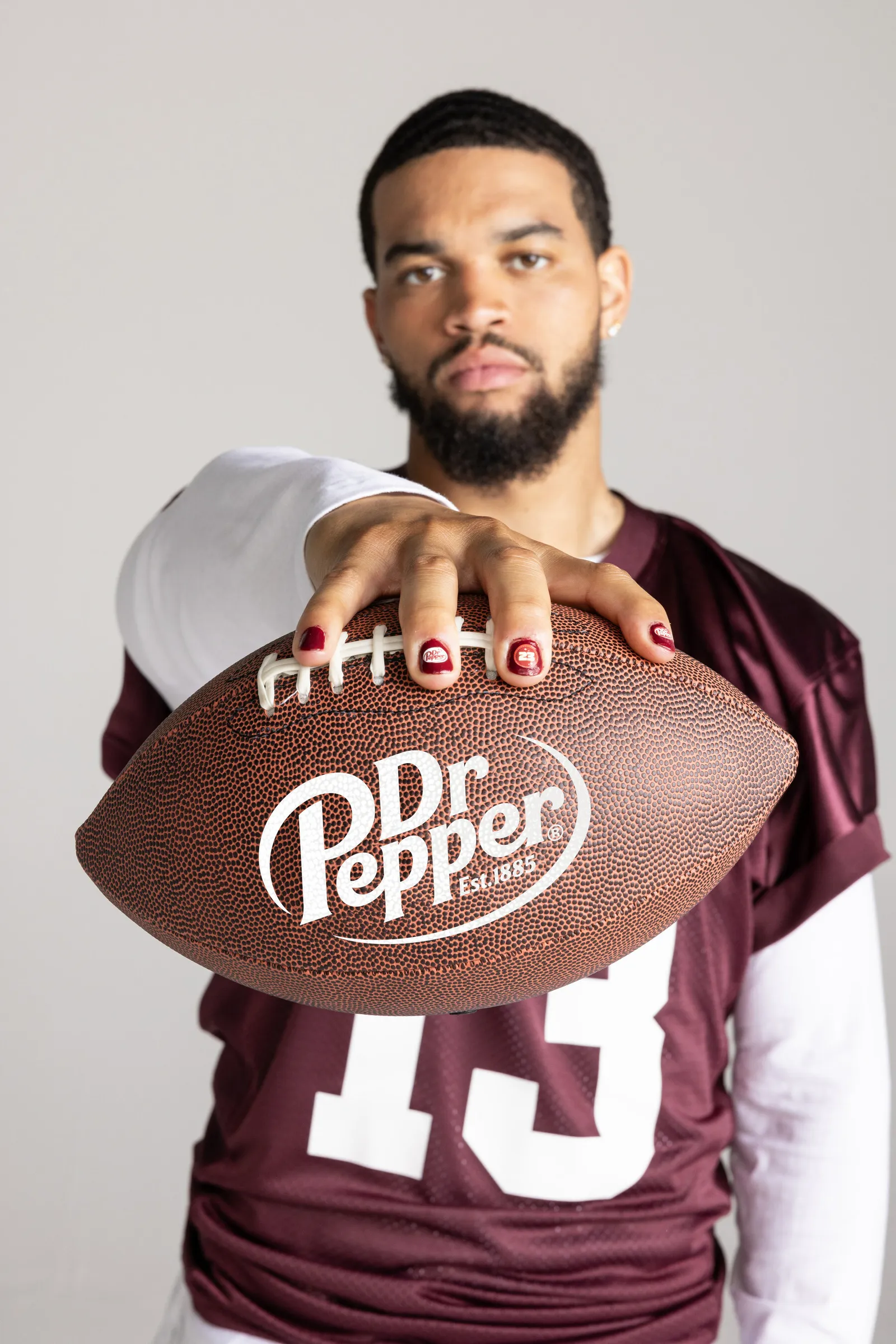 Caleb Williams sostiene un balón de fútbol con sus manos cuidadas para Dr Pepper