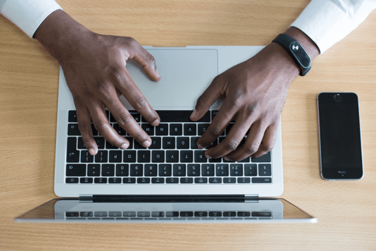 Un hombre escribe en una computadora portátil.