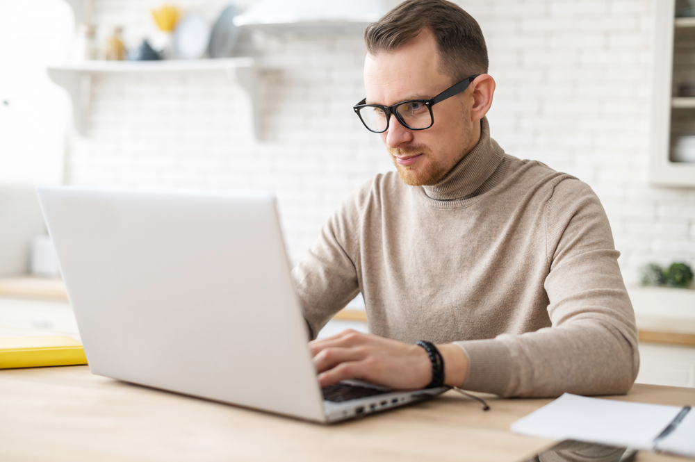 hombre inteligente con anteojos usando una herramienta de optimización en su laptop