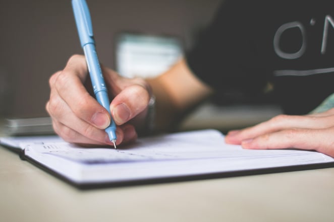 mãos escrevem em um caderno aberto