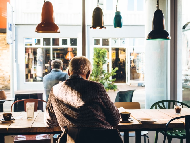 a parte de trás da cabeça de dois homens sentados em um café em frente a uma janela