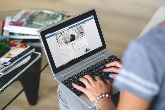 la donna digita su un laptop con una scheda del browser aperta su Facebook