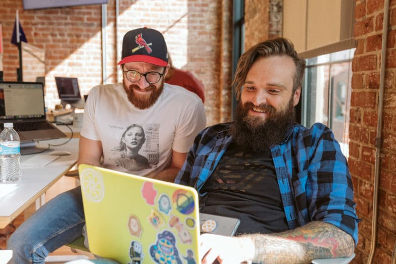 Deux hommes souriants alors qu'ils travaillent sur leur SEO WordPress eCommerce.