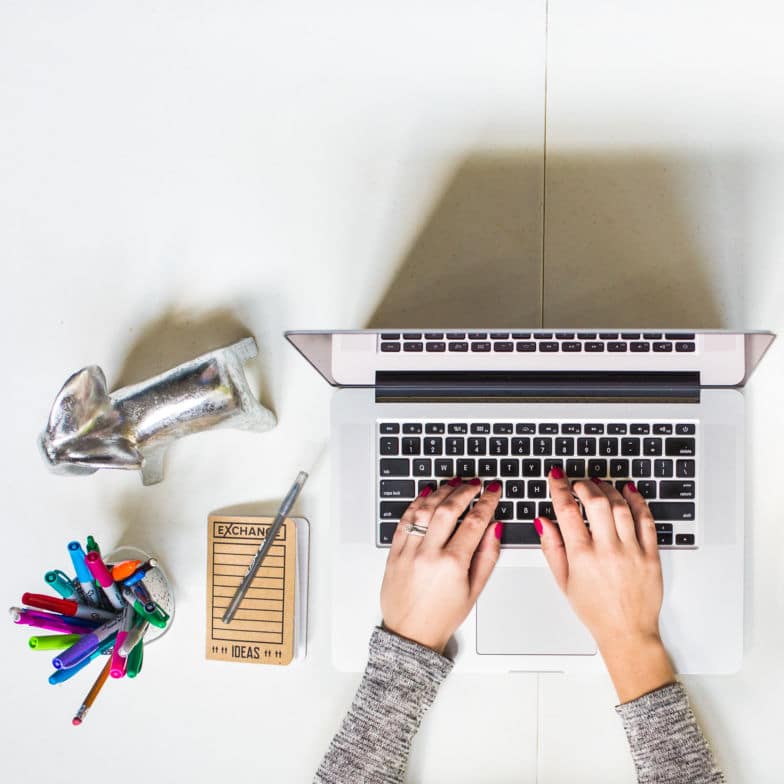 photo aérienne d'un concepteur de sites Web avec des ongles peints en rouge tapant sur un ordinateur portable