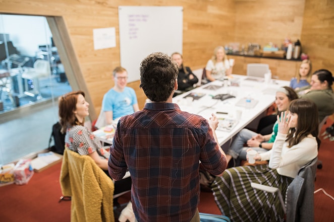 layout por perguntas do volante para perguntar aos clientes antes de iniciar o projeto de web design homem falando com um grupo de pessoas sentadas à mesa