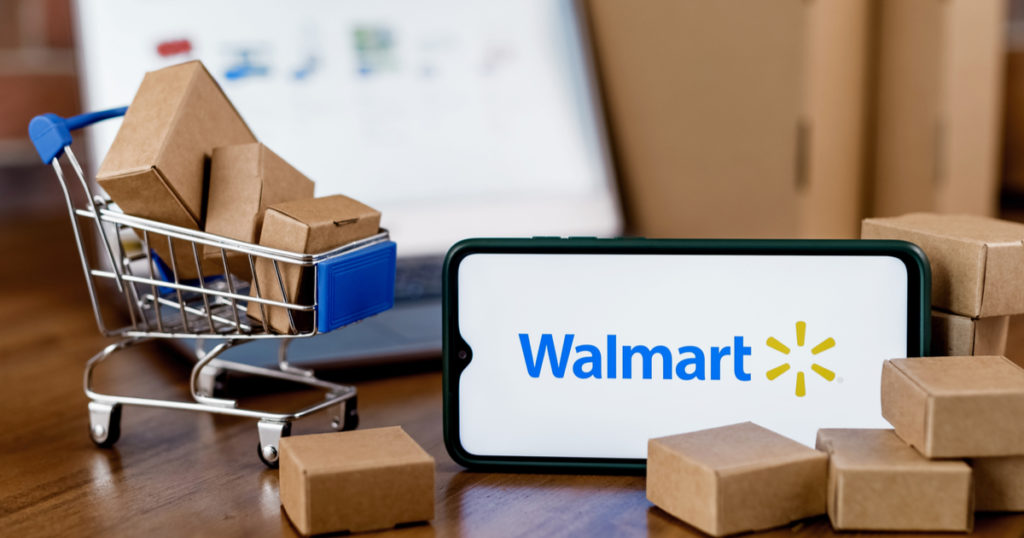 Aplicativo Walmart em um smartphone e um carrinho de compras em miniatura com pacotes saindo