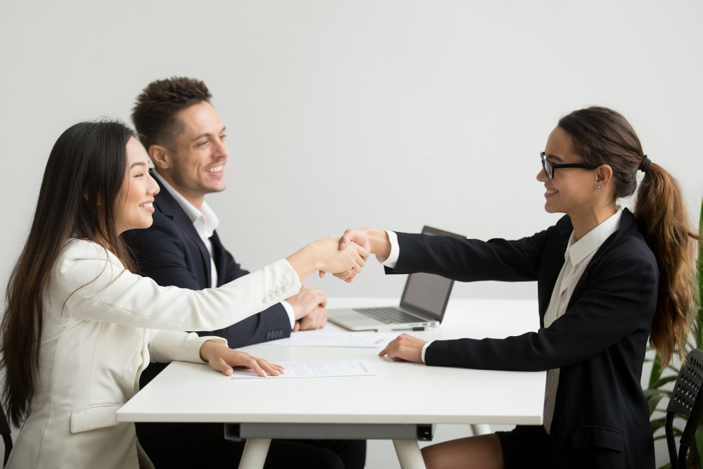 Diversas empresarias sonrientes se dan la mano en la reunión del grupo